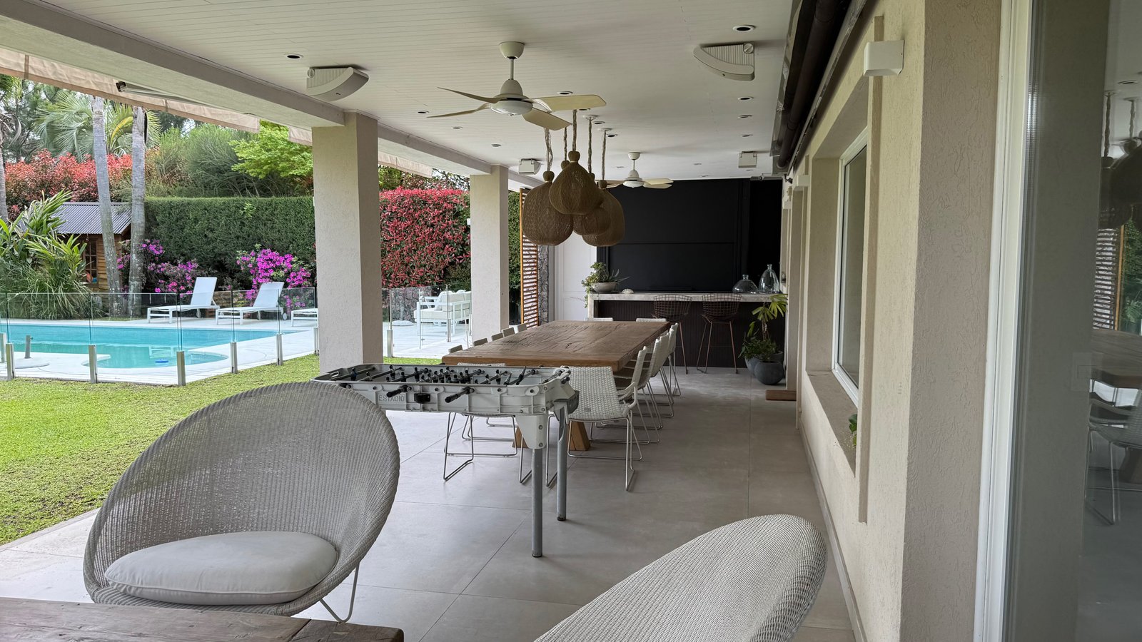 Amplo pátio semi-aberto com piscina e vegetação exuberante — projeto CASA CM, por Hermann Arquitectos, em Los Castores